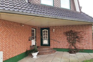 A brick house with a green door, a small porch, and a potted plant. - Holiday apartment in Büsum with swimming pool (Büsum)