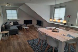 A modern loft-style living space with a dining area, a sofa set, a flat-screen TV, and a fireplace. - Holiday apartment in Büsum with swimming pool (Büsum)