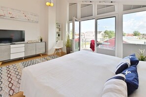 A modern bedroom with a large bed, a TV, a bookshelf, and a balcony with a view. - Home port at the Bodden market (Glowe)