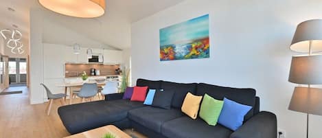 Un salon moderne avec un canapé d’angle, une table basse en bois et un tableau accroché au mur.