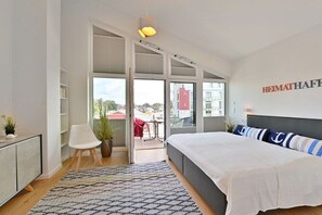 A modern bedroom with a large bed, a view through the glass door, and a bookshelf. - Home port at the Bodden market (Glowe)