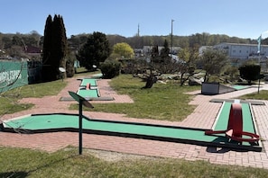 Ein Minigolfplatz mit mehreren grünen Spielbahnen und roten Hindernissen.