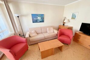 A furnished living room with a sofa, two armchairs, a coffee table, a TV, and artwork on the walls. - Holiday apartment "Little Seagull" (Ostseebad Sellin)
