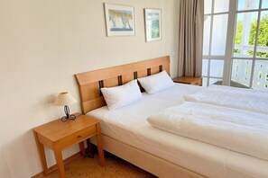 Une chambre d’hôtel avec un lit, une table de chevet, une lampe et deux tableaux encadrés au mur.