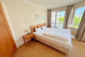 Ein Hotelzimmer mit einem großen Bett, einem Nachttisch und einem mit Vorhängen versehenen Fenster.