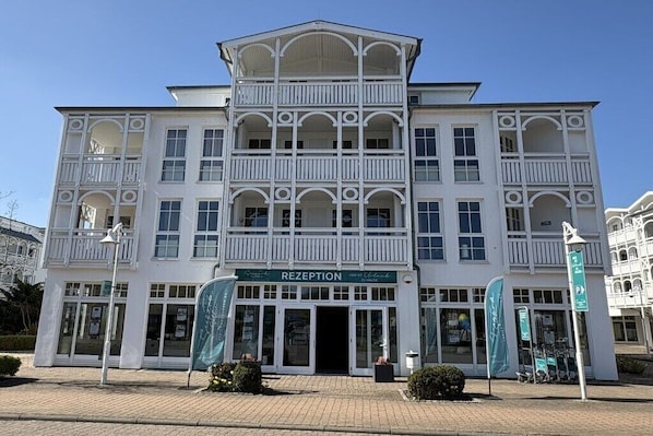 Ein mehrstöckiges Gebäude mit einer Rezeption, Balkonen und blauem Himmel.