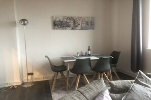 A dining area with a table and chairs, a floor lamp, and a couch with cushions. - Holiday apartment with 1 bedroom (Bremen)