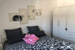 Un dormitorio con cama, almohadas, armario y decoración en la pared.