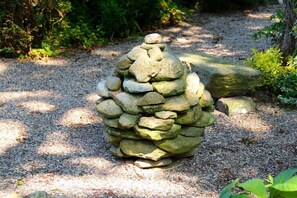 Eine aus Stein geformte Struktur, die einer Kiefernzapfe nachempfunden ist, in einem Garten.