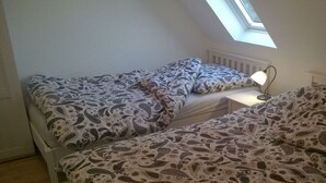 Ein Schlafzimmer mit zwei Betten, einem Dachfenster und einer Nachttischlampe.