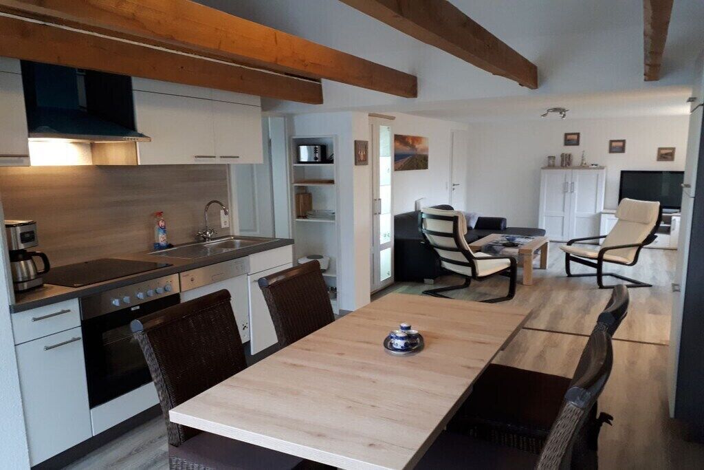 A compact kitchen with modern appliances, a dining area with a table and chairs, and a living space with a sofa and TV.