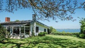 Una casa amb hivernacle de vidre, una xemenea i vista al mar.