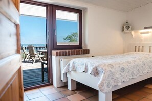 A bedroom with a bed, a window, and a view of the outside. - Terrace house by the sea (Langballig)