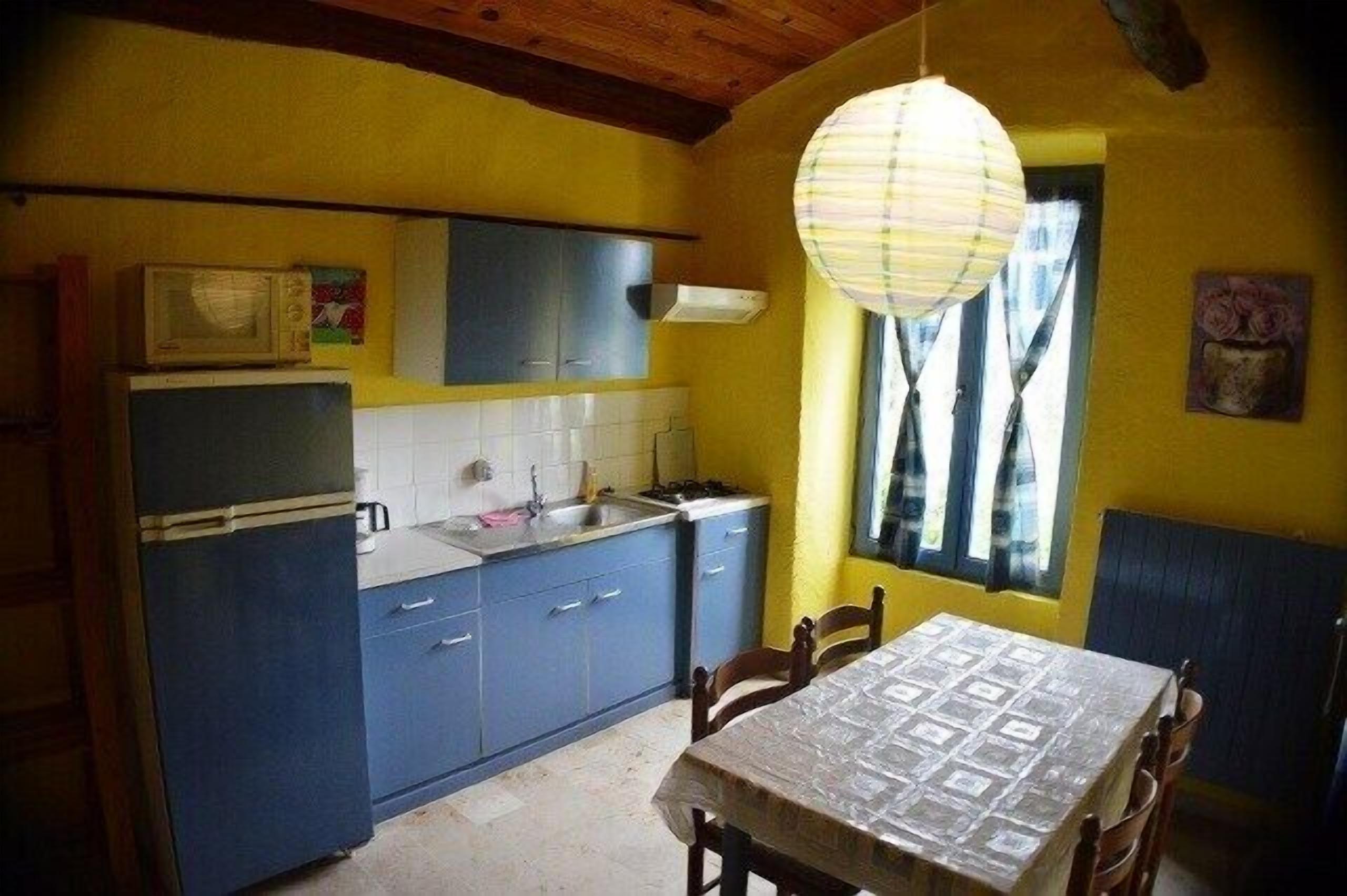 Eine Küche mit blauen Schränken, einer Mikrowelle und einem Tisch mit Stühlen.