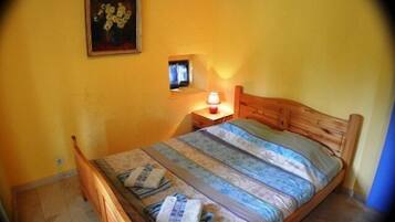Um quarto com uma cama de madeira, uma mesa de cabeceira com abajur e um quadro na parede.