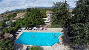 A rectangular swimming pool with a stone border, surrounded by lounge chairs and a fence. - Vrbo Property (Grospierres)