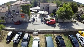 Um estacionamento com vários carros, um edifício com uma placa e montanhas ao fundo.
