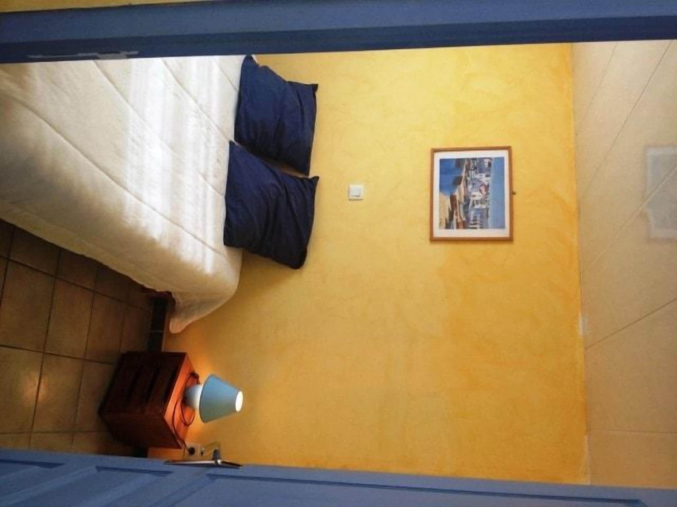Um quarto com uma cama, uma luminária, um quadro na parede e um armário de madeira.