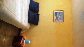 Um quarto com uma cama, uma luminária, um quadro na parede e um armário de madeira.