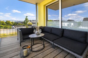 A balcony with a black sofa, a round table, and a vase with flowers. - Winterberg City & Ski (Winterberg)