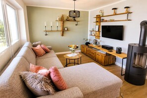 A living room with a sofa, a coffee table, a TV, a fireplace, and wooden shelves with decorative items. - Winterberg City & Ski (Winterberg)