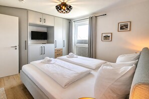 A hotel room with a bed, a TV, a wardrobe, and a window with curtains. - Winterberg City & Ski (Winterberg)