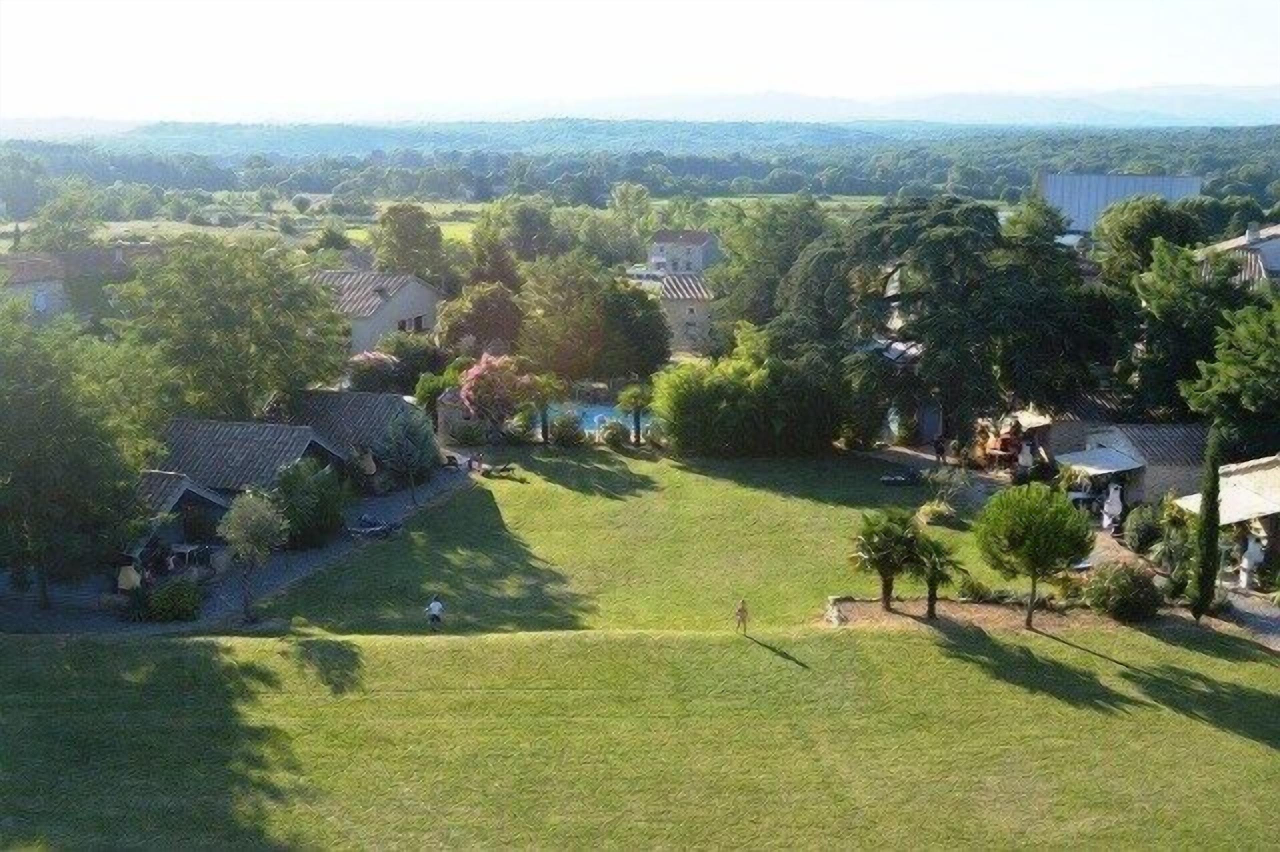 A residential area with houses, a grassy field, and trees.