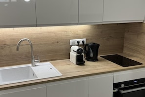 A kitchen with a modern sink, a coffee maker, and a black induction cooktop. - Alpine Ski Apartment in Tignes for 4 (Orcières)