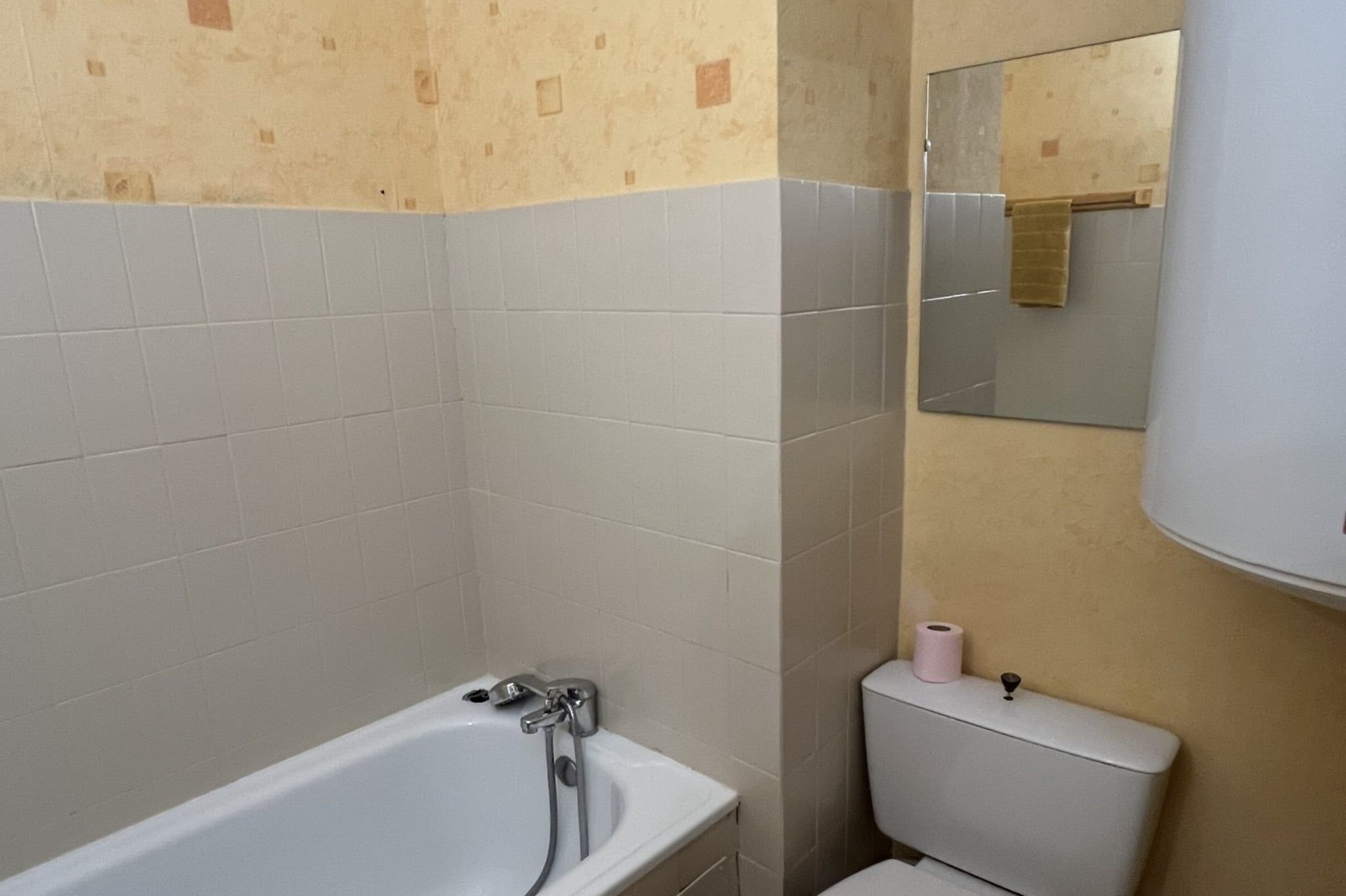 Un baño con bañera, inodoro y espejo.