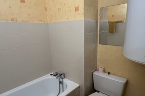 A bathroom with a bathtub, toilet, and a mirror. - Alpine Ski Apartment in Tignes for 4 (Orcières)