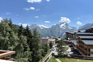 Une station de montagne avec des bâtiments en bois, un parking et, en arrière-plan, des sommets enneigés.