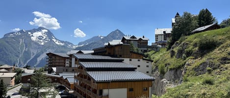 A mountain lodge with multiple wooden buildings, a parking area, and a view of snow-capped mountains.