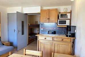 Eine kompakte Küchenzeile mit Holdekor-Schränken, einer Mikrowelle, einem Toaster und einer Kaffeemaschine.