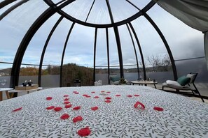 A room with a large bed, a table with chairs, and a view of the outdoors through a glass ceiling. - Charming Couple Getaway in Bouillon (Bouillon)