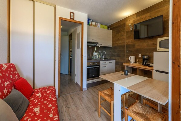 A compact living space with a kitchenette, a dining area, and a sofa with red cushions. - Grand Horizon 2 N°210 - 2P6C (Morillon)