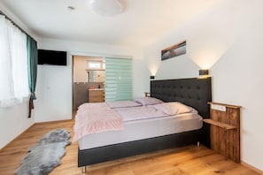A modern bedroom with a bed, a wooden floor, a fur rug, and a wall-mounted TV. - Chalet in Stuhlfelden near Ski Slopes (Stuhlfelden)