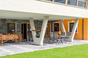 An outdoor patio with a dining table and chairs, a wooden bench, and a potted plant. - Chalet in Stuhlfelden near Ski Slopes (Stuhlfelden)