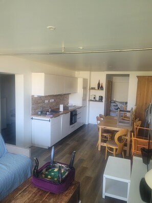 A modern kitchen with white cabinets, a brick backsplash, and a dining area with wooden chairs and a table. - 2-Bedroom Apartment with Pool, Mountain View, Shared Pool, and Balcony (Chamrousse)
