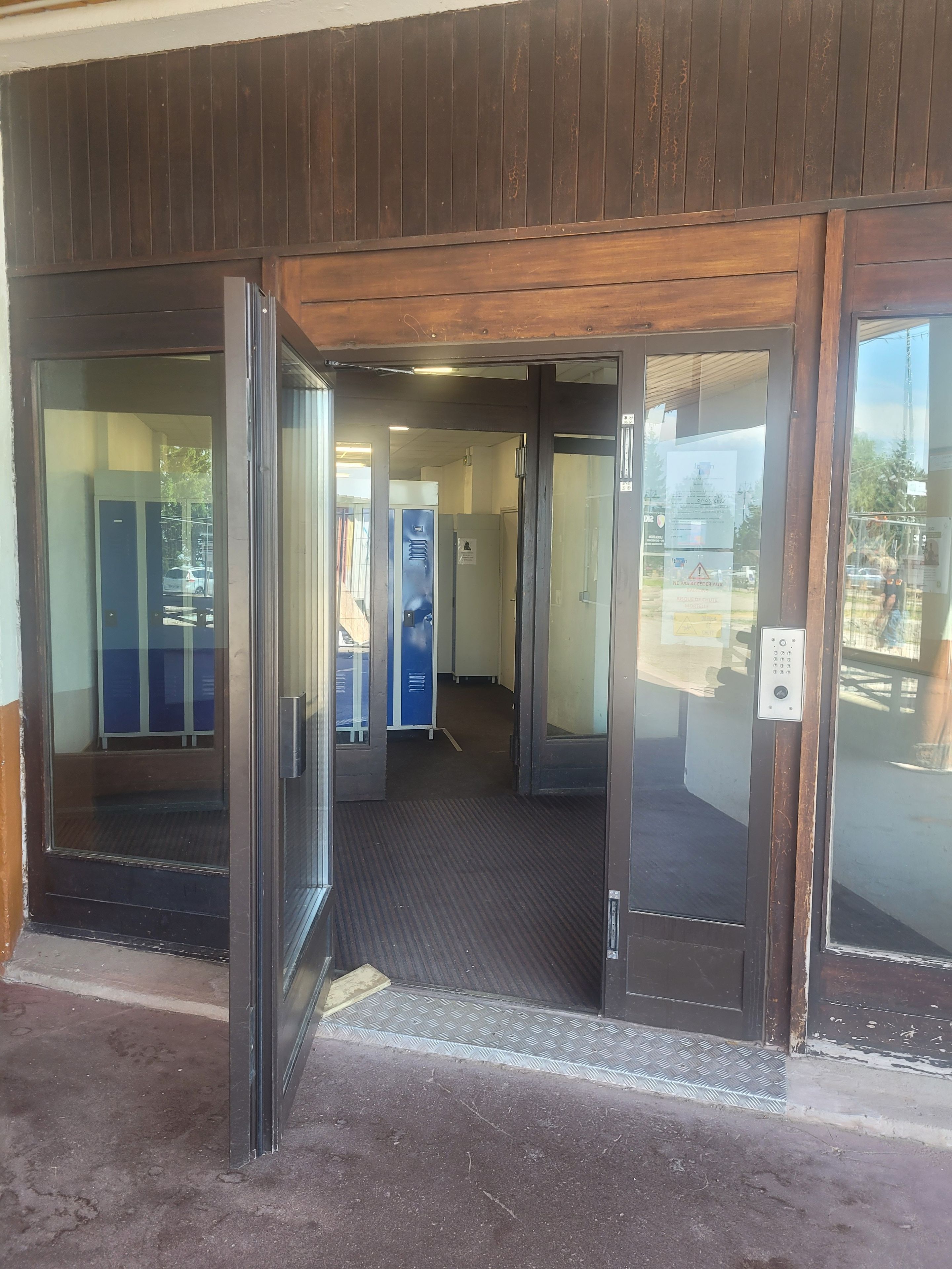 An entrance with a glass door, a carpeted floor, and a blue locker.