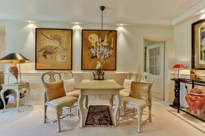 A dining area with a table and chairs, a chandelier, and two large framed artworks on the wall. - Holiday home Dünensand (Kampen)