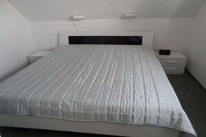 A bedroom with a bed, a nightstand, a drawer, and two bedside tables. - Holiday home with 2 bedrooms (Wangerland Hooksiel)