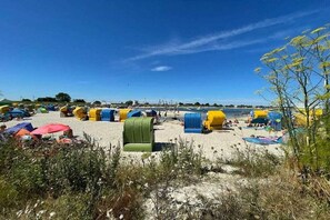 A beach with multiple colorful beach chairs and umbrellas. - North Sea air Burhave (Butjadingen)