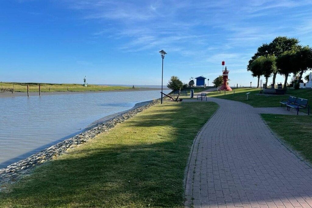 Une promenade au bord de la rivière, agrémentée d’un phare rouge, de bancs et d’un lampadaire.