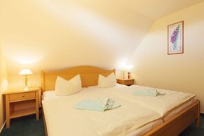 A single bed with a wooden headboard, two bedside tables with lamps, and a framed picture on the wall. - Kiekenbusch Oben West (Groß Zicker)