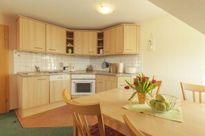 Una cocina compacta con armarios de madera, una isla central y una zona de comedor con sillas y una mesa.