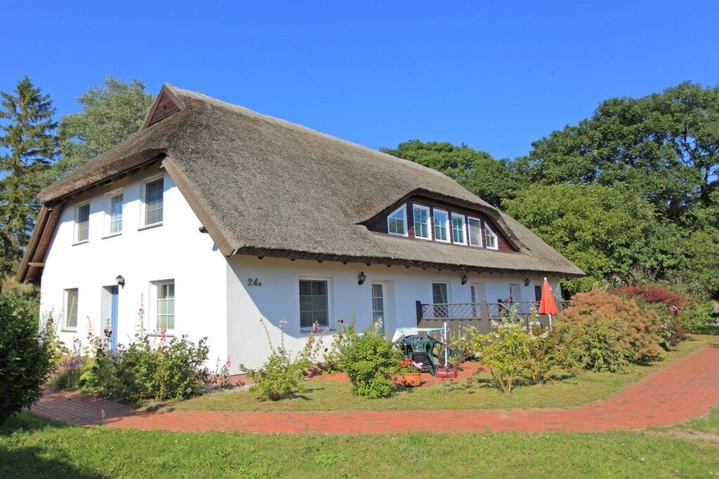 Ein traditionelles Haus mit einem steilen, strohgedeckten Dach, einer weißen Fassade und einem kleinen Vordach.
