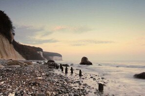 A rocky beach with a cliff, calm sea, and a clear sky. - Kiekenbusch Oben West (Groß Zicker)