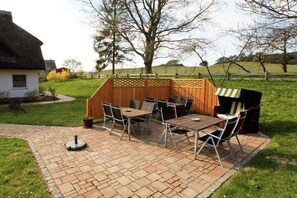 An outdoor patio with a wooden table and chairs, a grill, and a small shed. - Kiekenbusch Oben West (Groß Zicker)