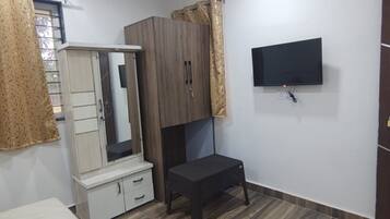 Un dormitorio con cama, armario, televisor y un reloj en la pared.
