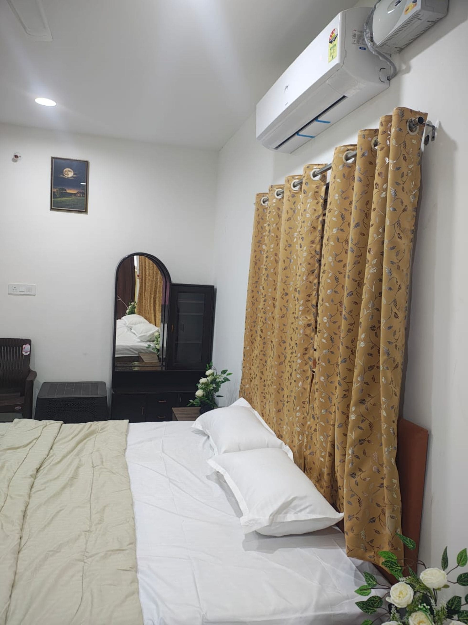 Een hotelkamer met een bed, een spiegel, een dressoir, een airconditioner en een raam met gordijnen.